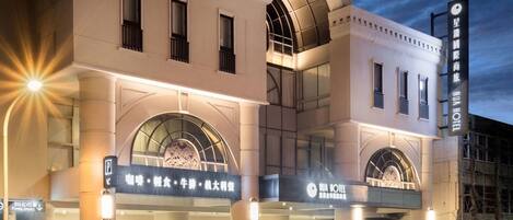 A hotel with a modern facade, large arched windows, and a sign indicating amenities such as dining and a spa.