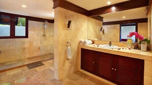 A bathroom with a shower, a sink, and a large mirror.