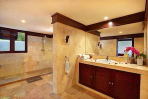 A bathroom with a shower, a sink, and a large mirror.