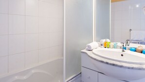 A bathroom with a bathtub, a sink, and a mirror. - Lagrange L Oree DES Cimes (Les Angles)