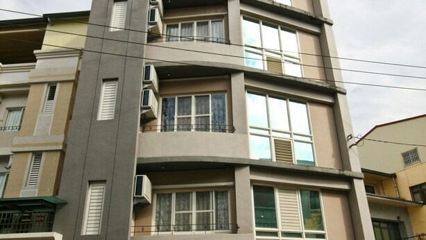 A multi-story residential building with a garage parking a white car. - Q House (Puli)