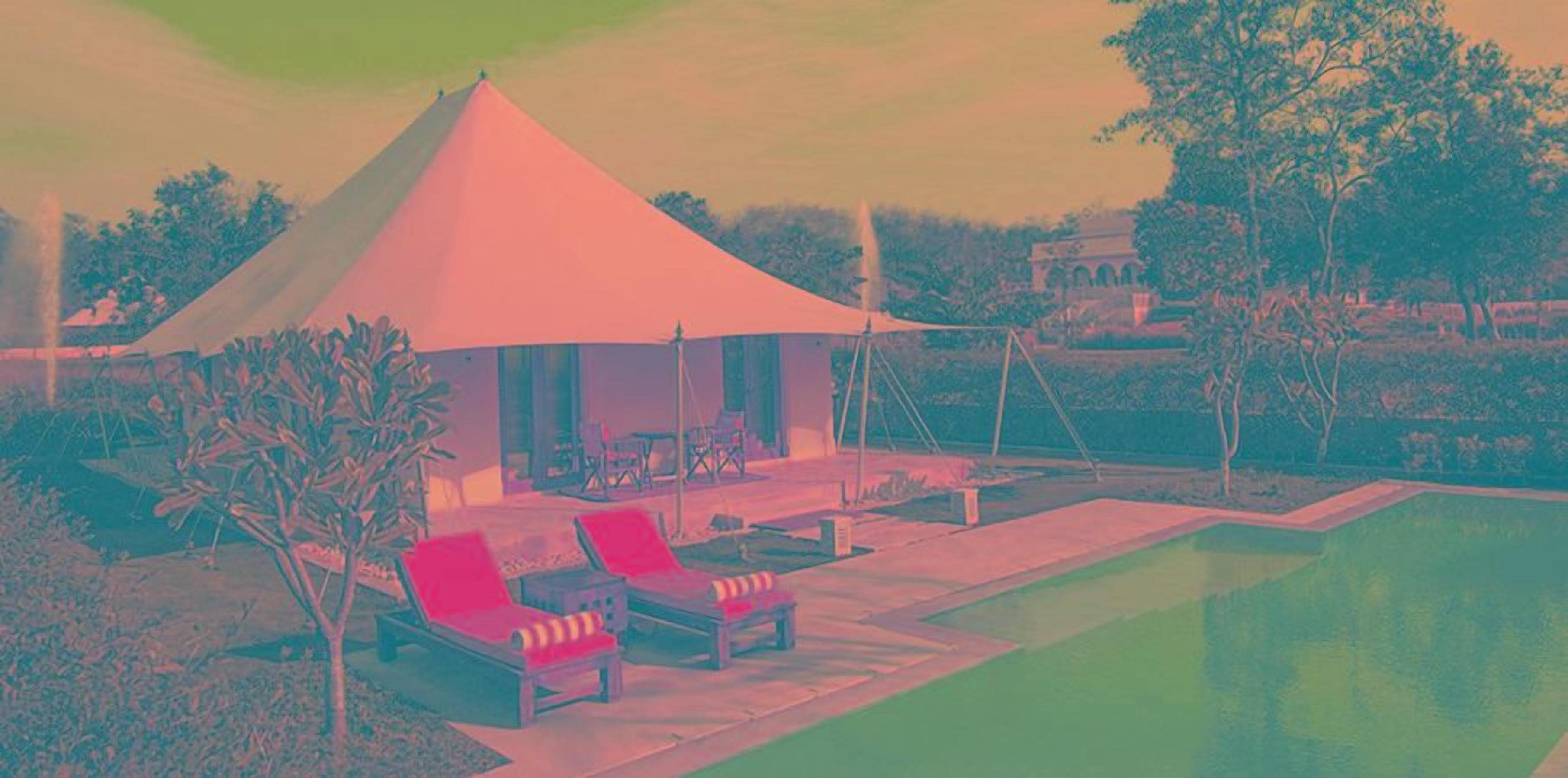 A tented outdoor area with lounge chairs and a pool.