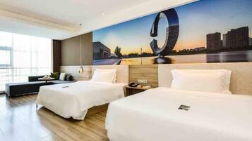 A hotel room with two beds, a large window, and a cityscape mural on the wall.
