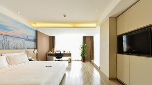 A hotel room with a large bed, a desk with a chair, a television, and a painting on the wall. - Atour Hotel Tianjin Teda (Tianjin)