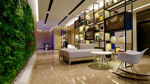 A modern lounge area with a sofa, a round table, and a rocking chair. - Atour Hotel Tianjin Teda (Tianjin)