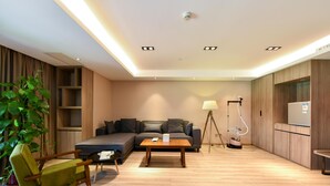 A modern living room with a sofa, a coffee table, a lamp, and a vacuum cleaner. - Atour Hotel Tianjin Teda (Tianjin)
