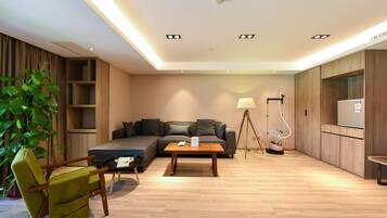 A modern living room with a sofa, a coffee table, a lamp, a vacuum cleaner, and a TV.