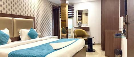 Une chambre d’hôtel avec un grand lit, un bureau, une chaise et un téléviseur.