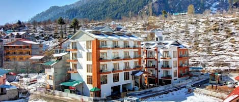 A multi-story hotel with balconies, located in a snowy mountainous area.