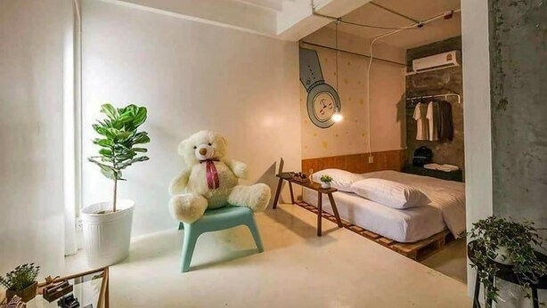 A small, cozy room with a bed, a chair, a potted plant, and a teddy bear. - Pastelhouse Hostel (Bangkok)