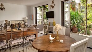 Un coin repas avec une table ronde en bois, des chaises et un téléviseur fixé au mur.