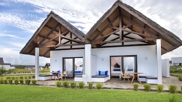 A two-story building with a thatched roof, large windows, and a patio area with seating.