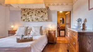 A bedroom with a bed, bedside tables, a dresser, and a hanging light fixture. - La Pieve Marsina (Gaiole in Chianti)
