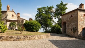 A stone building with a covered outdoor seating area and a gravel path. - La Pieve Marsina (Gaiole in Chianti)
