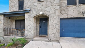 A stone building with a blue garage door, a front door, and a small porch area. - Family stay near Live Oak Park with patio, pool table, & soaker tub (Live Oak)