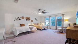 A bedroom with a bed, bedside tables, a desk, a chair, and a ceiling fan. - Family stay near Live Oak Park with patio, pool table, & soaker tub (Live Oak)