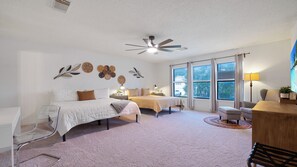 Quarto com cama, mesas de cabeceira, escrivaninha, cadeira e ventoinha no teto.