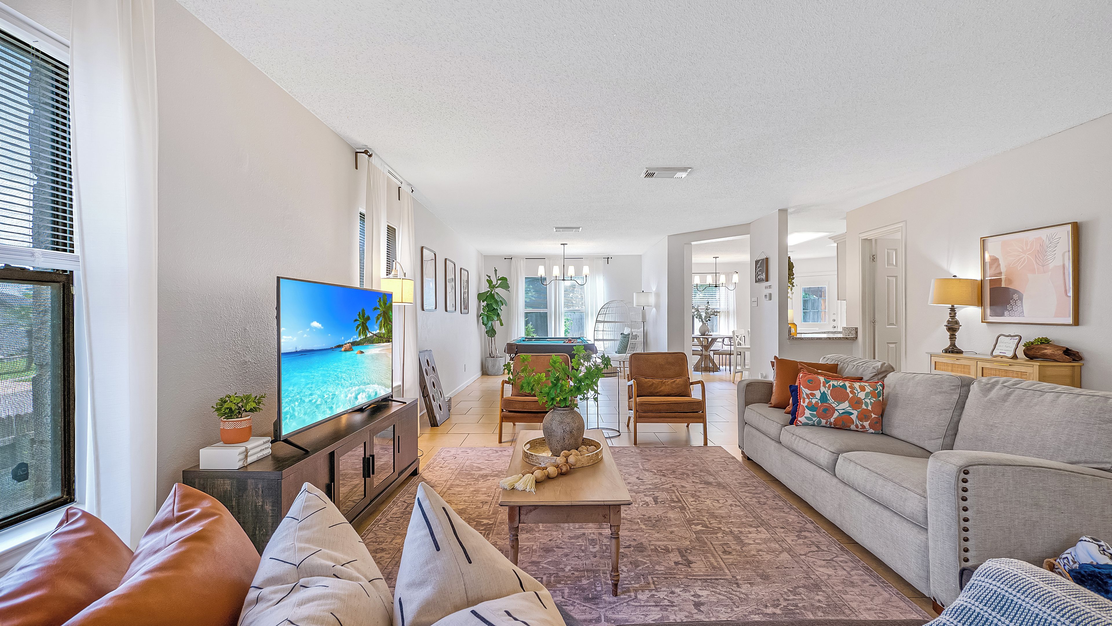 A spacious living room with a television, seating area, and a view of the dining area.