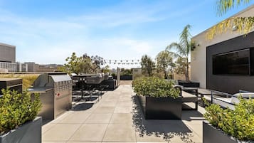 Une terrasse extérieure équipée d’un barbecue, de sièges et de jardinières.