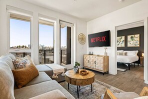 Ein modernes Wohnzimmer mit einer Couch, einem Couchtisch und einem an der Wand befestigten Fernseher.
