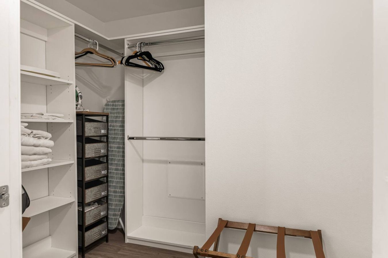 Um closet espaçoso com prateleiras, barra de metal para pendurar roupas e caixas organizadoras.