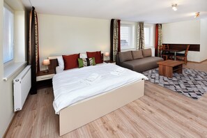 Un dormitorio con una cama grande, un sofá, una mesita y una ventana con cortinas.