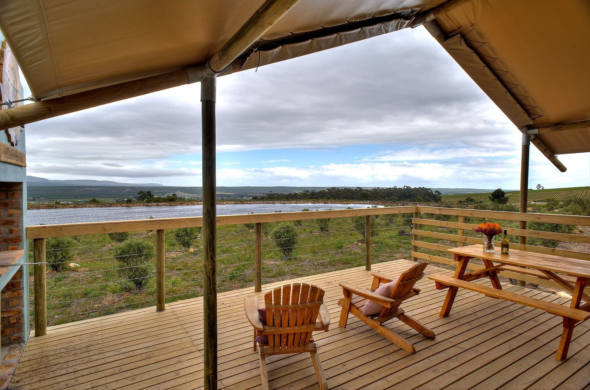 A wooden deck with a table and chairs overlooking a river and landscape.