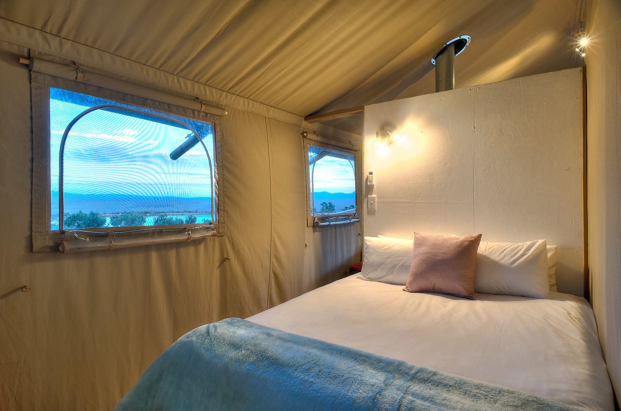 A bedroom with a bed, two windows, and a light fixture.