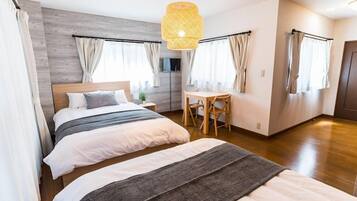 A hotel room with a large bed, a desk, and a hanging light fixture.