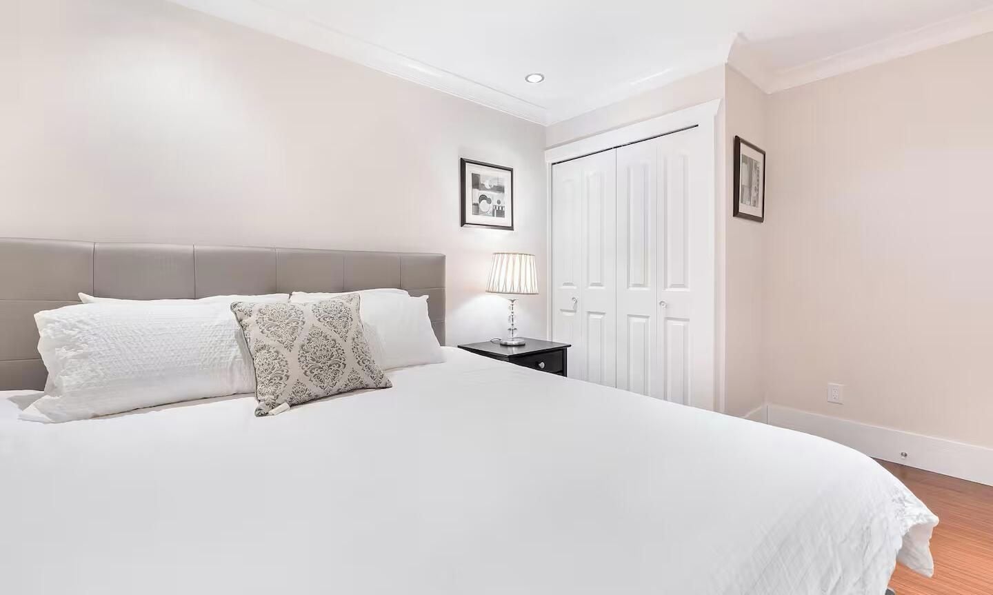 A bedroom with a bed, nightstand, lamp, and a door.