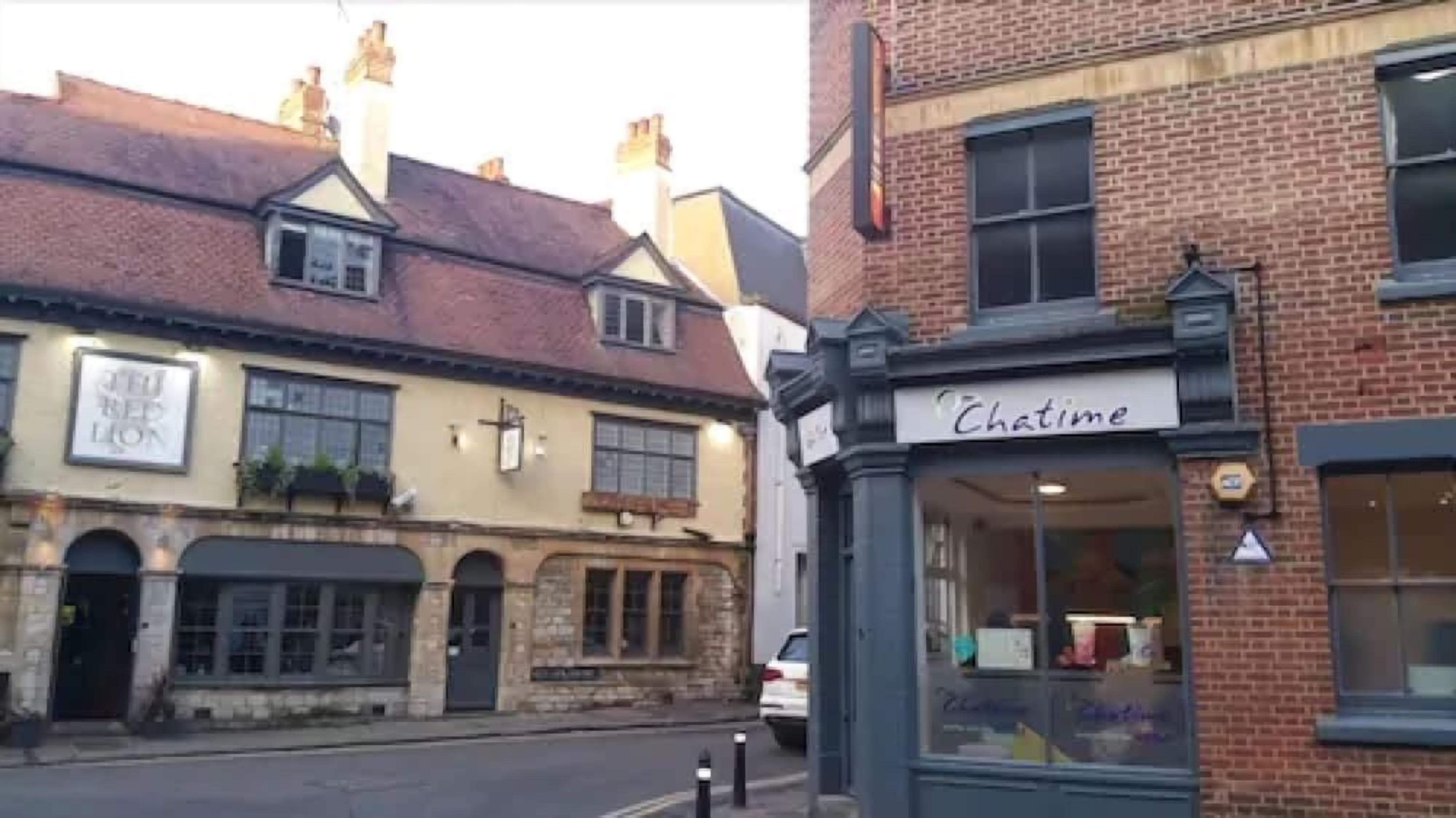 Une vue de rue avec un bâtiment portant l’inscription « Chatime » et un autre bâtiment avec une enseigne « THE LION ».