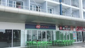 A multi-story building with a DQ Express restaurant on the ground floor, green chairs outside, and a Pizza Hut across the street. - Smdc Wind Residences by Bem (Tagaytay)
