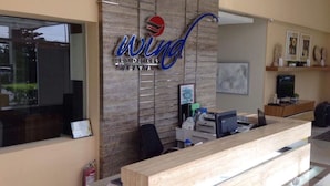 A reception desk with a logo above it, a computer, a printer, and a water bottle on the counter. - Smdc Wind Residences by Bem (Tagaytay)