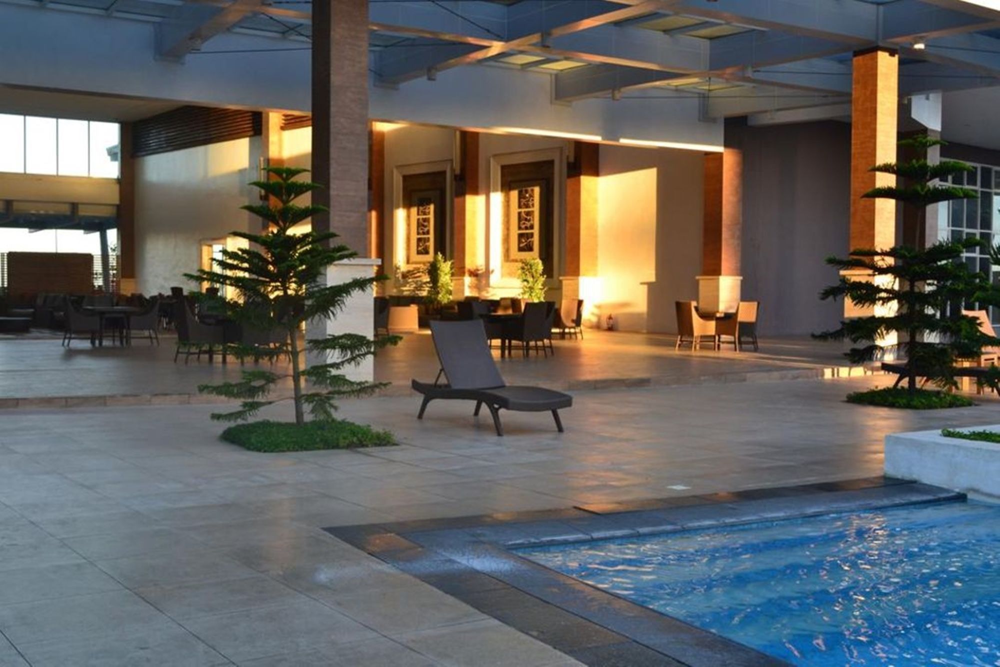 A hotel lobby with a pool, seating areas, and a reception desk.