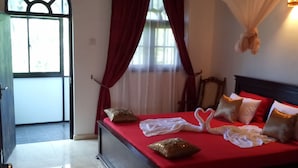 Un dormitorio con cama, cortinas, una ventana y una colcha.
