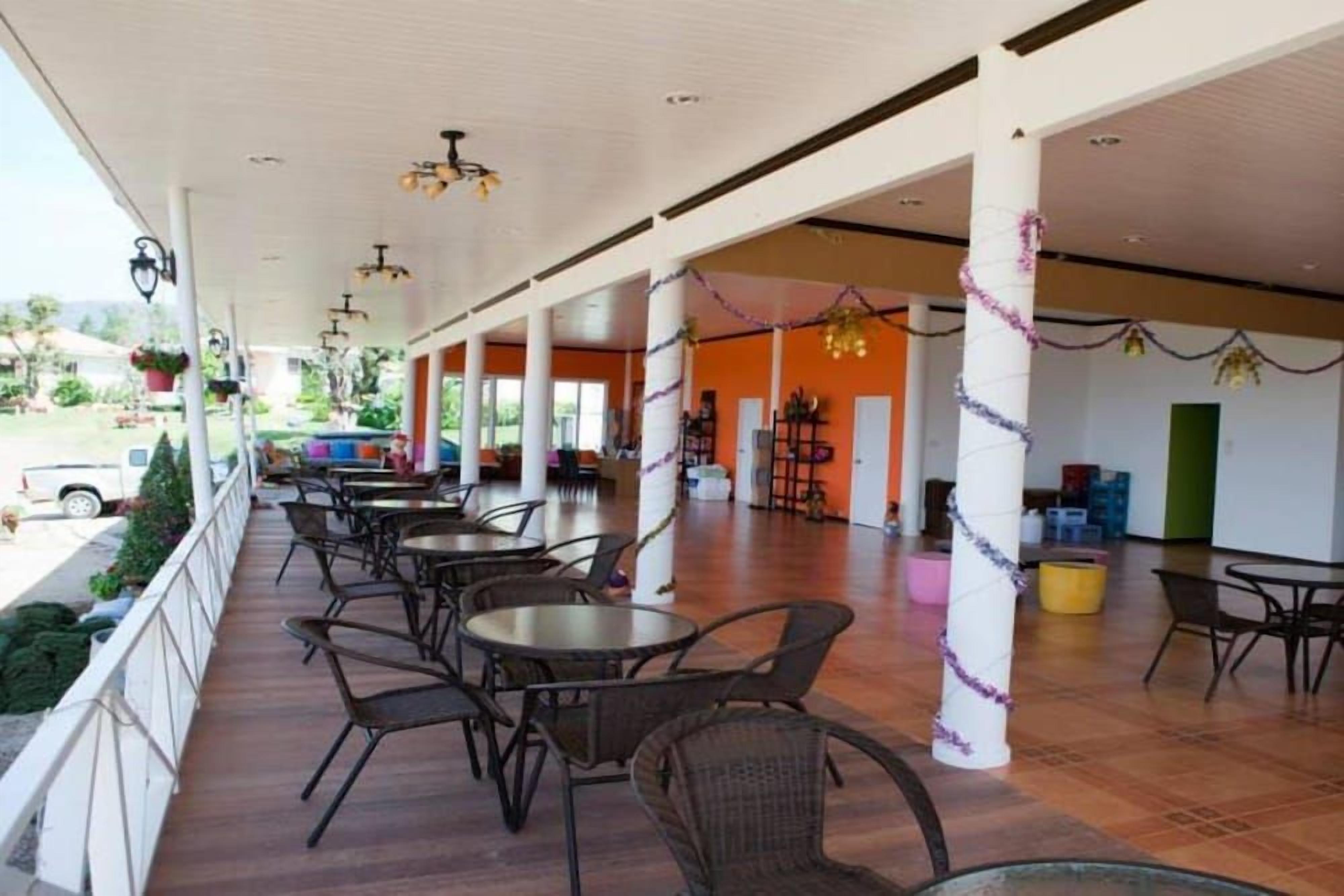 Un patio interior con mesas y sillas, un corredor cubierto y vistas al exterior.