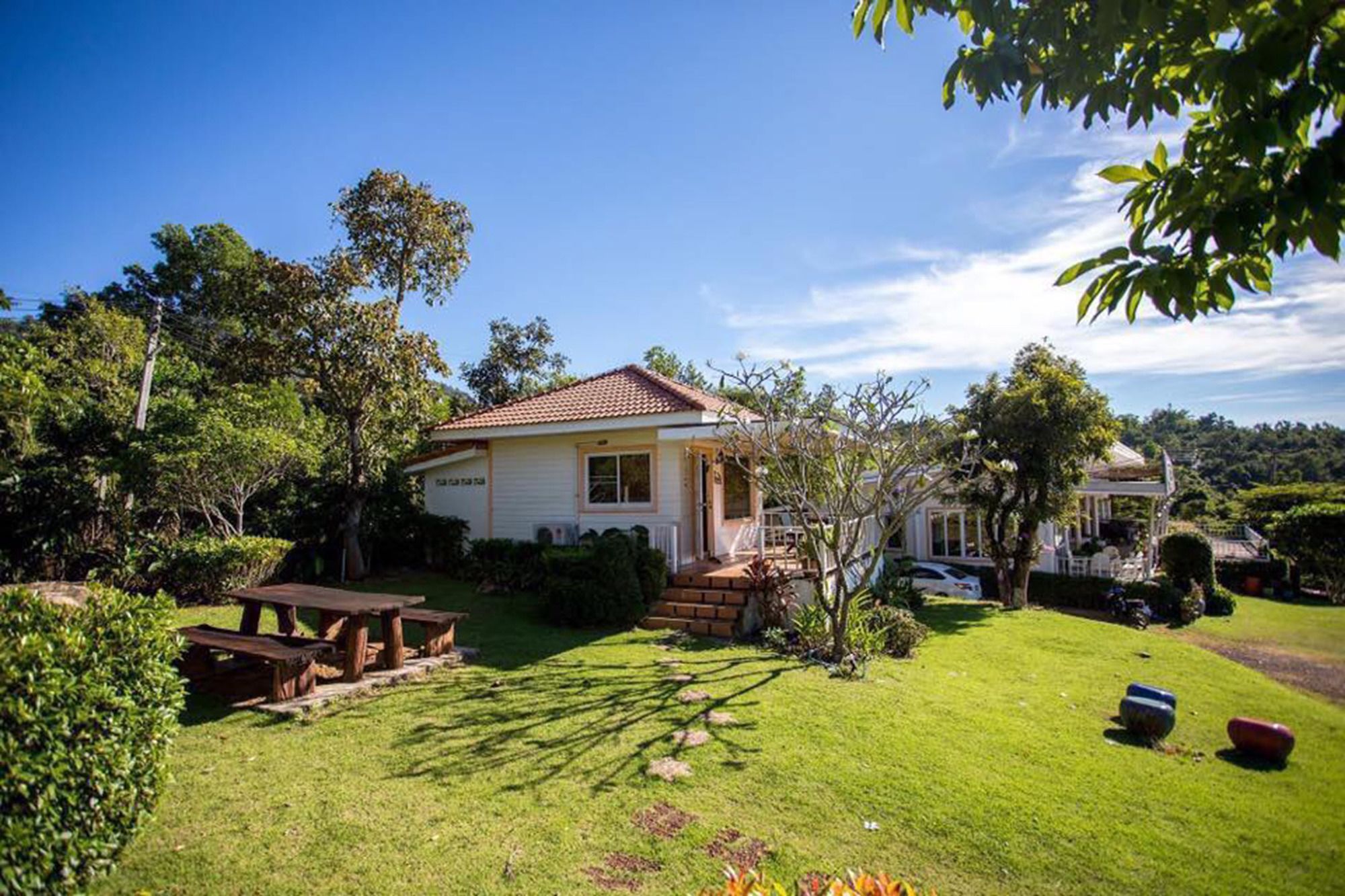 Una casa con patio, rodeada de vegetación y un cielo despejado.