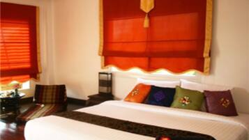 Habitación de hotel con una cama grande, una mesita de noche, una silla y un ventanal con persianas.