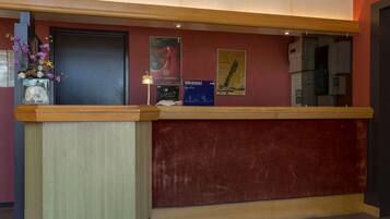 A reception desk with a wooden counter, a vase of flowers, and posters on the wall.