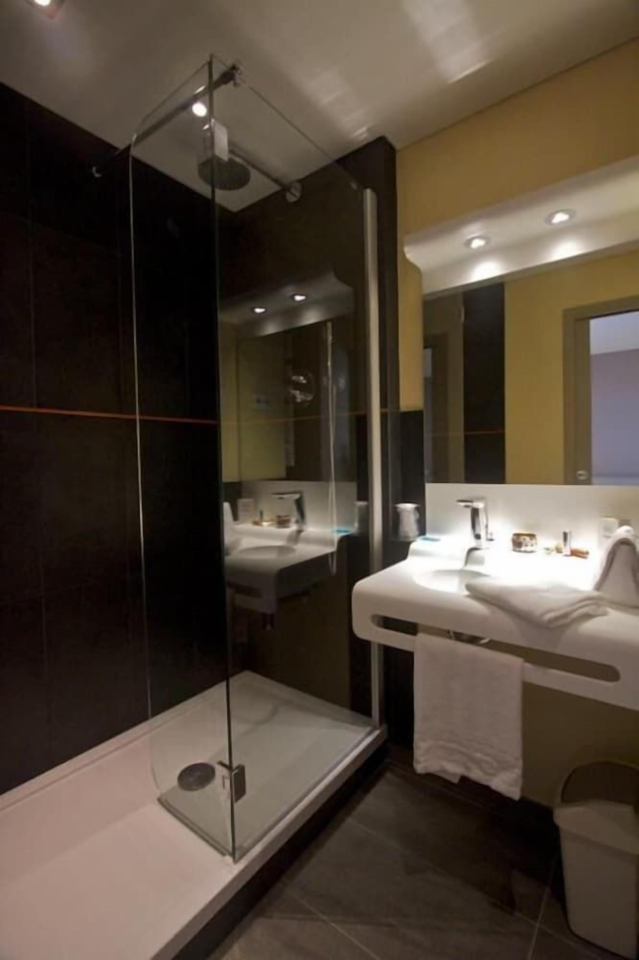 A modern bathroom with a glass-enclosed shower, a white sink, and a mirror above the sink.