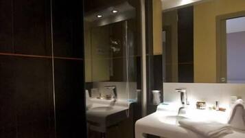A modern bathroom with a glass-enclosed shower, a white sink, and a mirror above the sink.