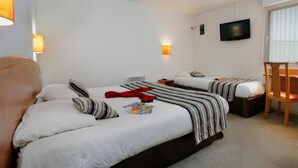 Hotellihuone, jossa on kaksi sänkyä, televisio ja tuoli.