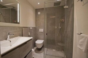 Un bagno moderno con doccia vetrata, lavandino bianco e water.