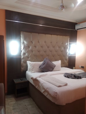 Een hotelkamer met een groot bed, een nachtkastje en een plafondventilator.