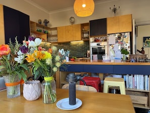 A kitchen with wooden cabinets, a central island, and a variety of flowers in vases.