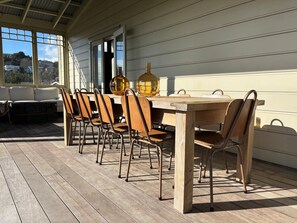 Un área de comedor al aire libre con una mesa y sillas de madera, un tazón decorativo grande y vistas del paisaje circundante.