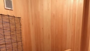 Une salle de sauna en bois avec une grande baignoire ronde rouge et une étagère en bois.