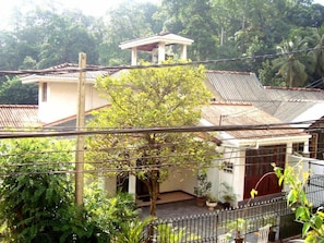 A residential building with a tiled roof, surrounded by lush greenery and a fenced garden. - Layathraa Hotel and Restaurant (Kandy)