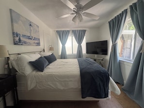 A bedroom with a bed, a ceiling fan, a TV, and curtains. - Kayaks, Bikes, Beach, Pennekamp 1 mile, walk to restaurants & shops (Key Largo)