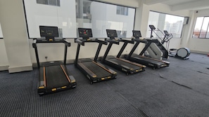 Four treadmills in a room with a window and a stationary bike. - 2-bedroom apartment in Nairobi near Jomo Kenyatta International airport (Nairobi)
